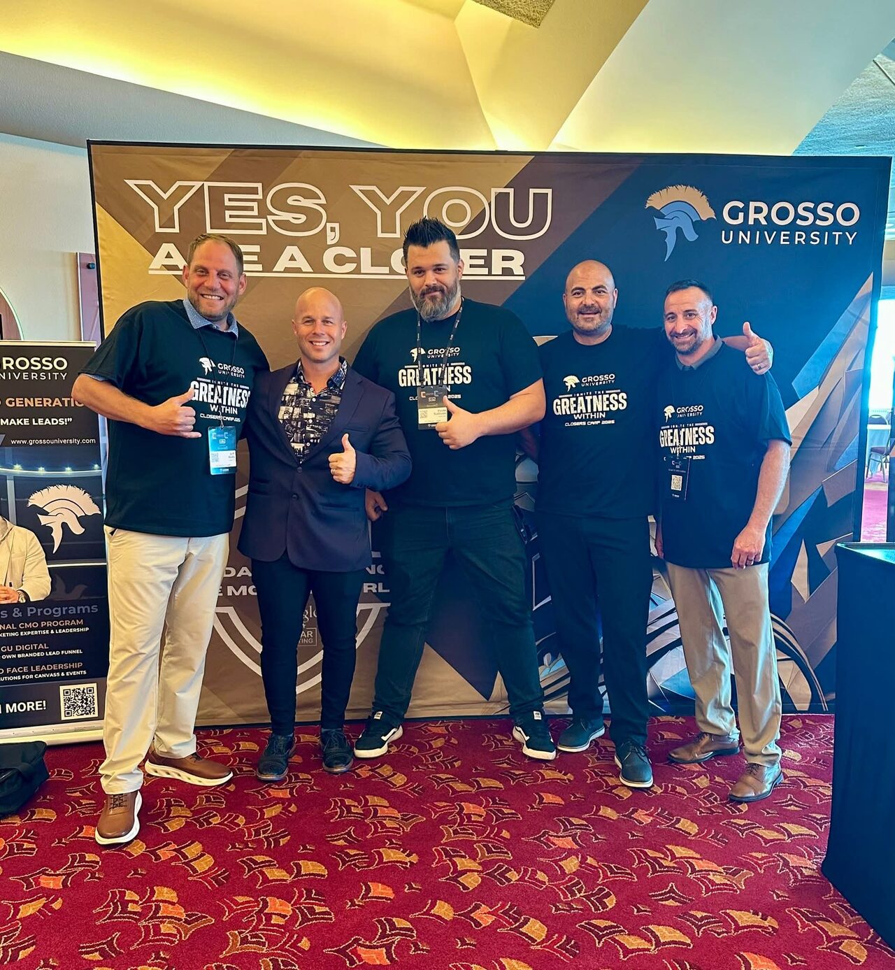 Five Closers Camp 2025 attendees in Grosso University shirts standing with Dominic Caminata in front of a branded backdrop reading "Yes, you are a closer".