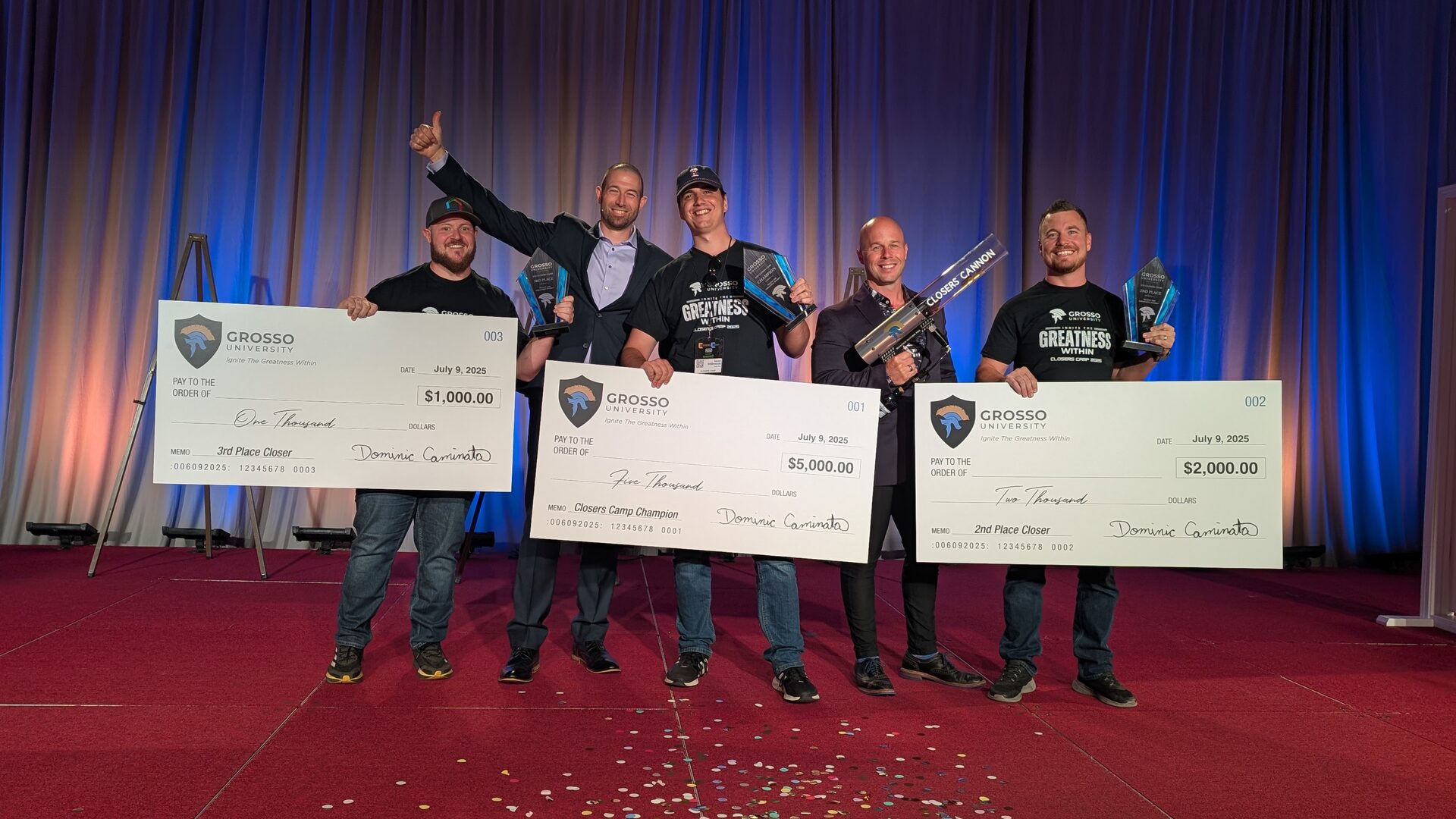 Closers Camp 2025 prize winners on stage with their oversized checks and trophies, joined by Grosso University staff, one raising a thumbs up.