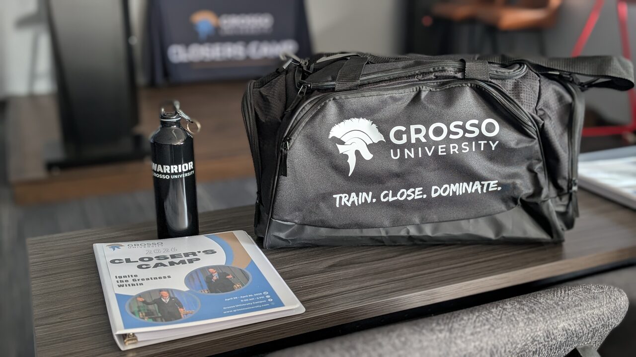 A Grosso University duffel bag reading "Train. Close. Dominate." on a table beside a Warrior water bottle and a Closer's Camp workbook.