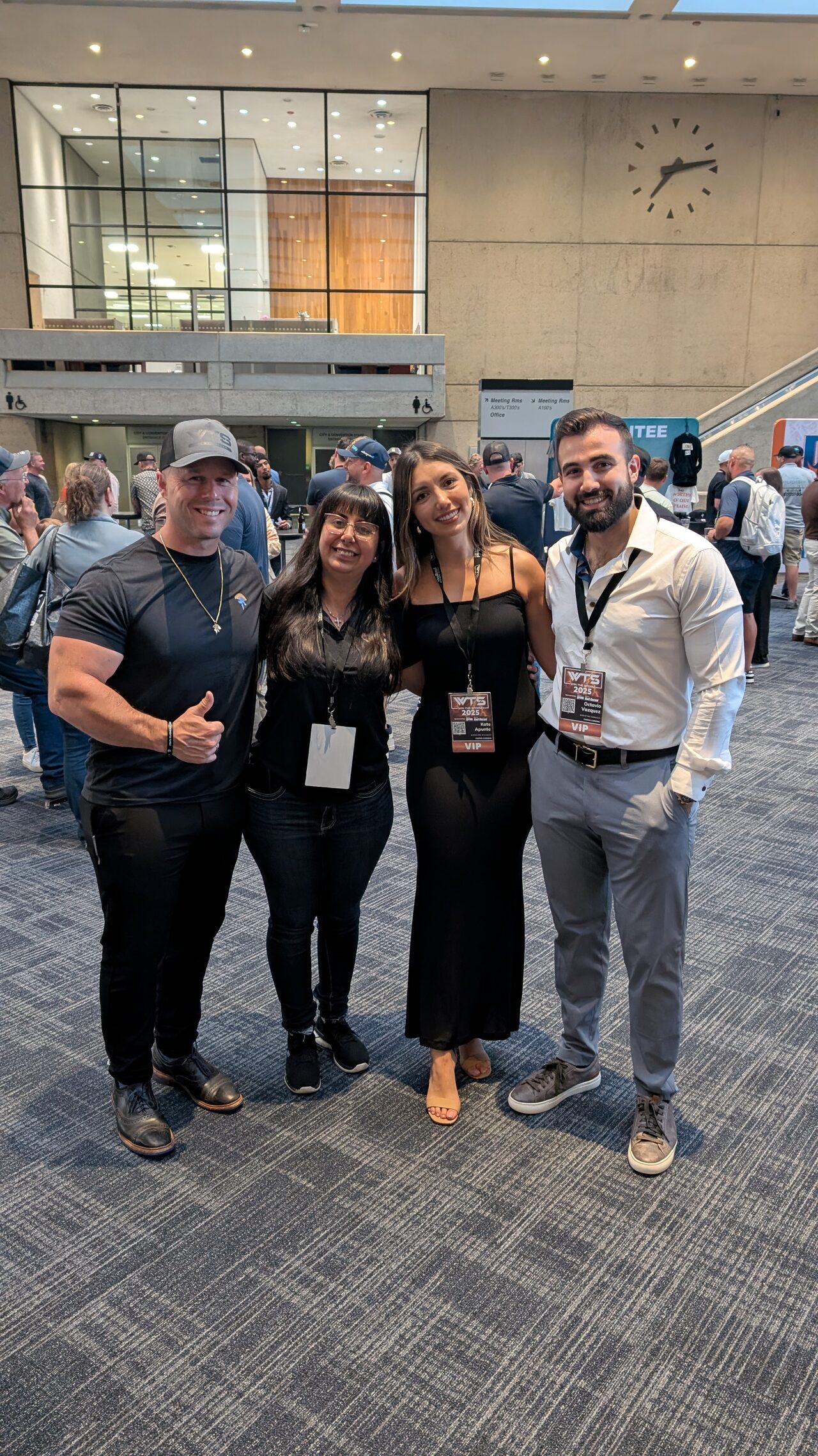 Dominic Caminata and Wendy Harmeyer with two colleagues, all wearing event badges, in a convention center lobby.