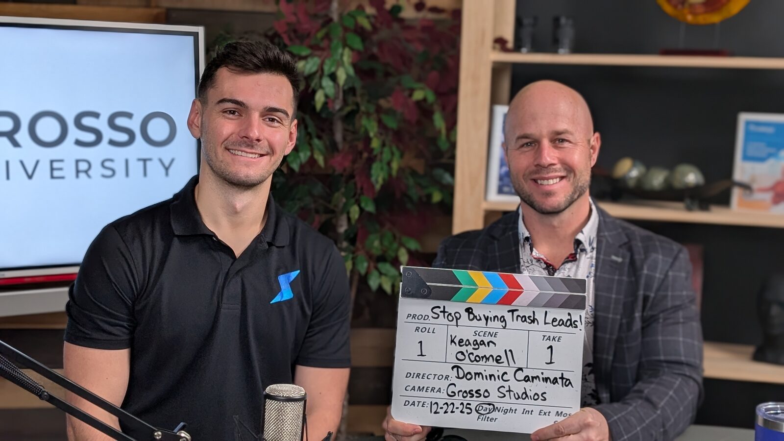 A guest and Dominic Caminata seated on the Grosso Studios set, Dominic holding a clapperboard labeled "Stop Buying Trash Leads".